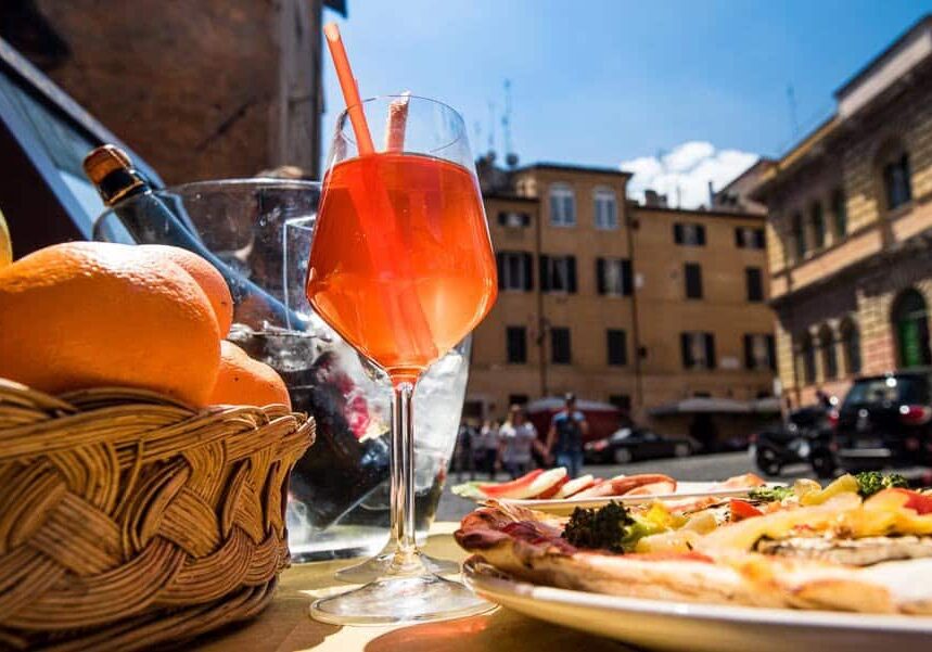 Aperol spritz cocktail and Italian pizza on a piazza Santa Maria in Trastevere. Rome . Italy